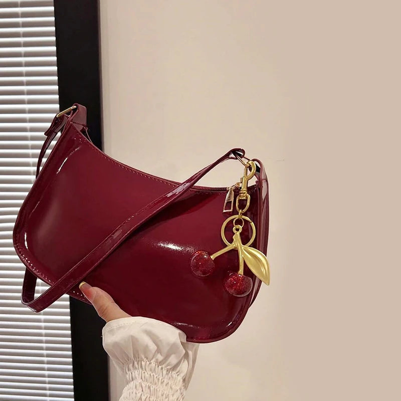 Elegant burgundy shoulder bag with gold cherry pendant detail