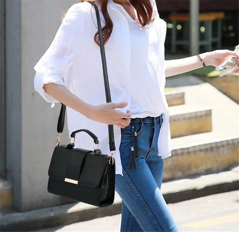 Chic woman wearing the black structured satchel bag as a crossbody, paired with a white shirt and jeans.
