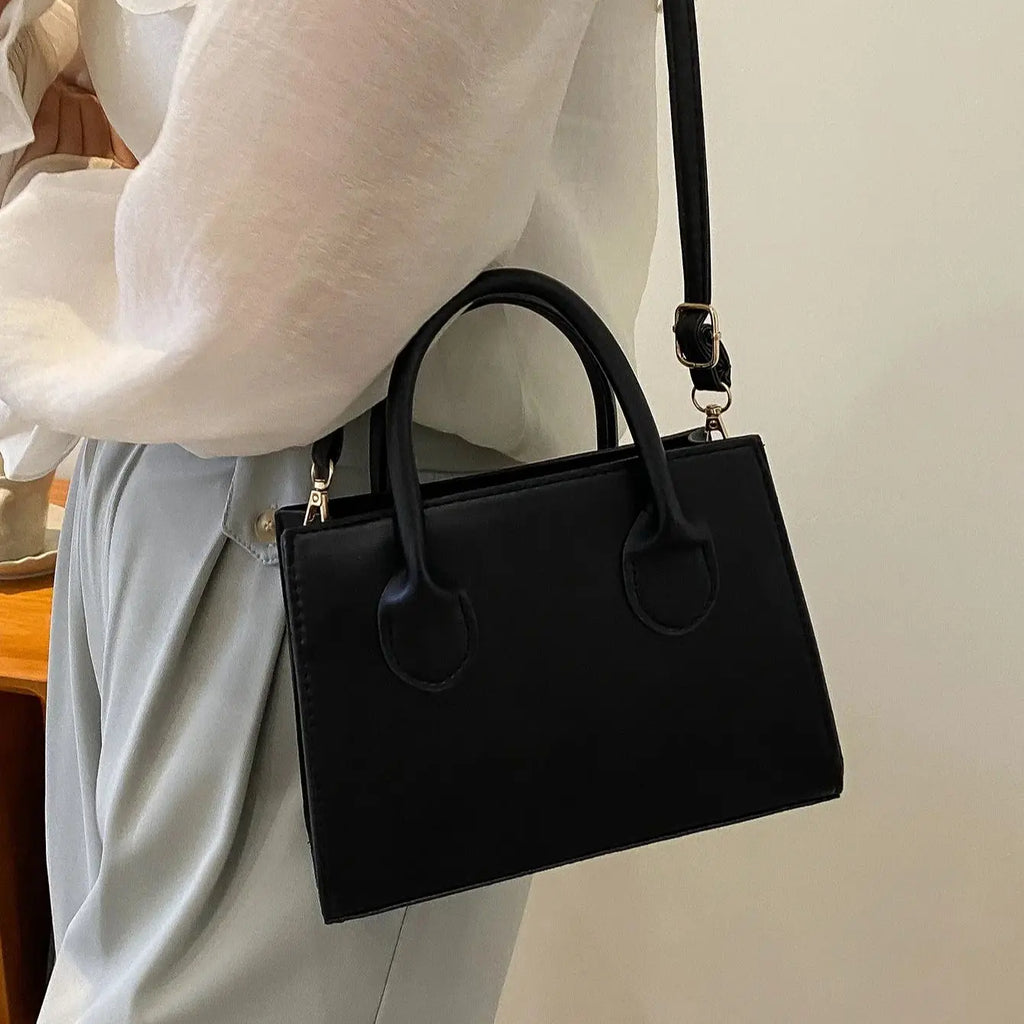 Elegant black structured top-handle handbag with detachable crossbody strap, showing measurements.
