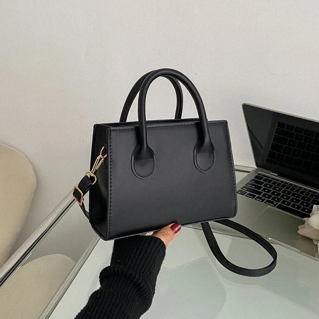 Elegant classic black handbag with top handle and adjustable shoulder strap for women