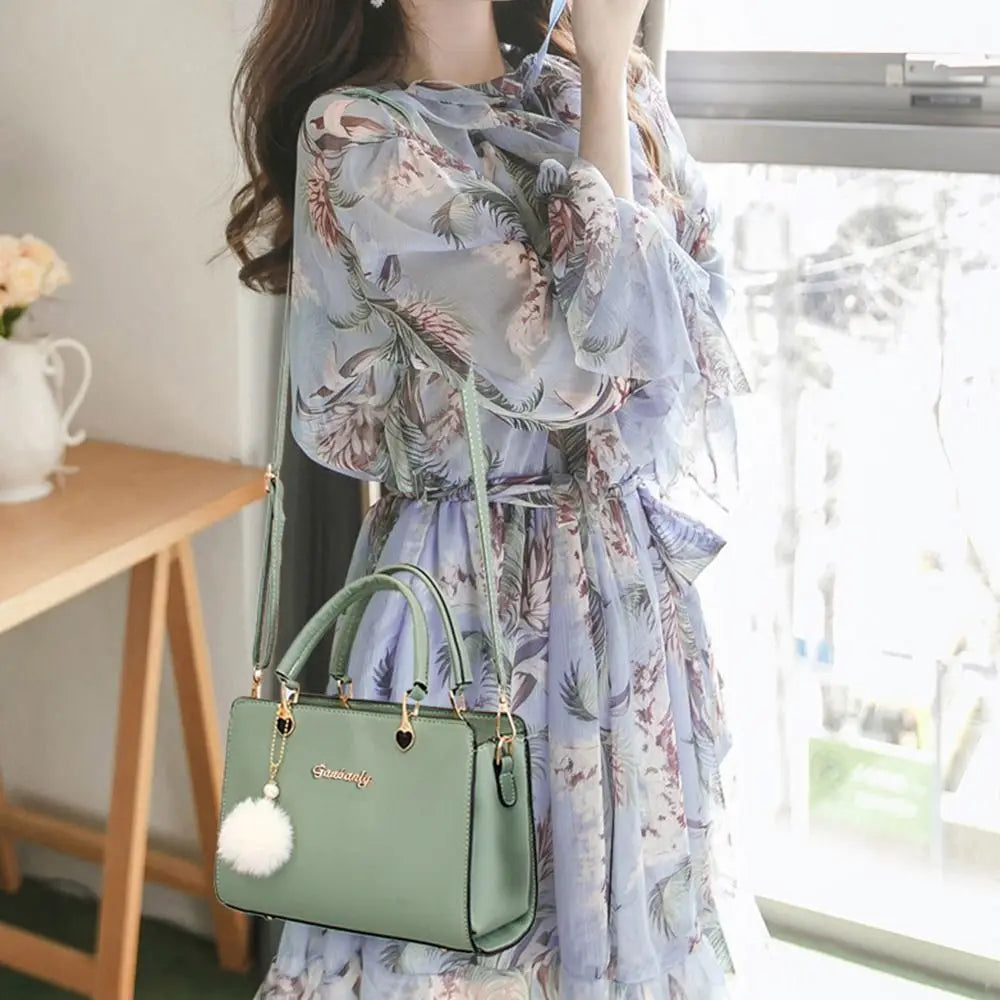 Elegant mint green handbag with top handle and gold hardware, carried by a model in a studio setting